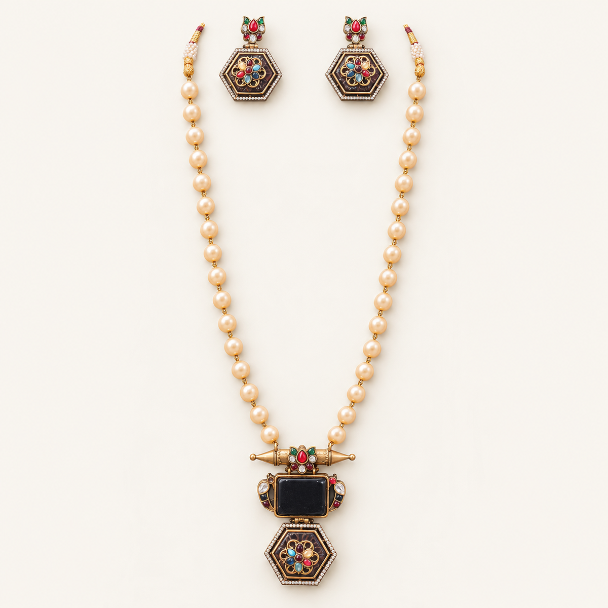 A gold-toned jewelry set featuring a pearl-beaded necklace with a decorative pendant and matching drop earrings, displayed on a clean off-white background.
