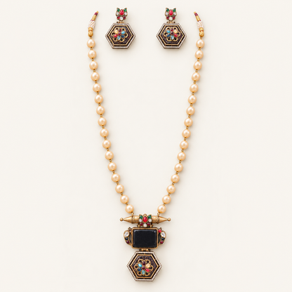 A gold-toned jewelry set featuring a pearl-beaded necklace with a decorative pendant and matching drop earrings, displayed on a clean off-white background.