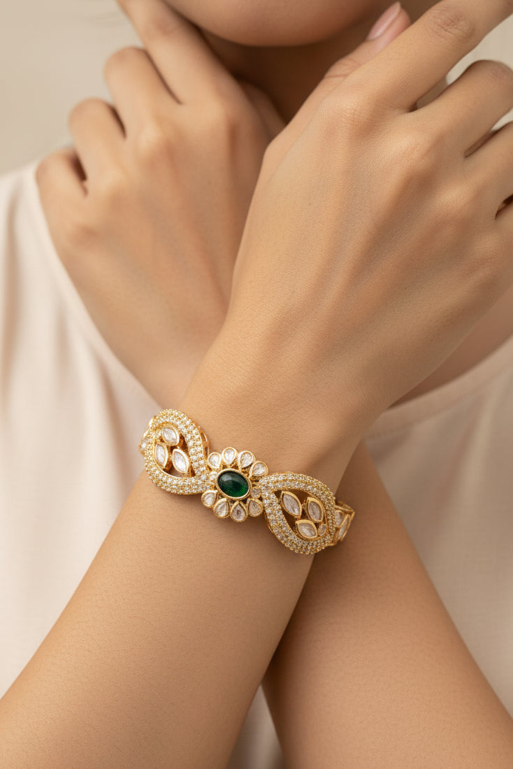 Gold bracelet with green gemstone on a white textured surface