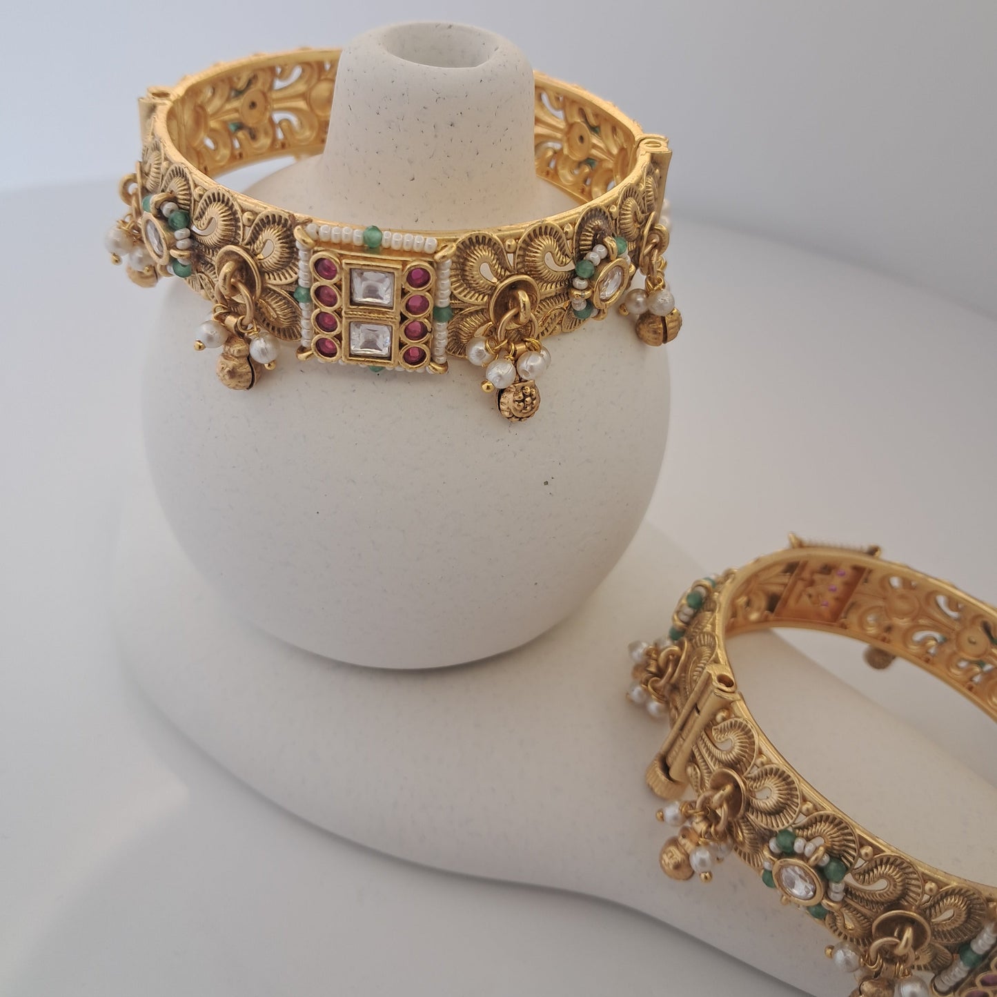 Gold bangles with gemstones on a white background