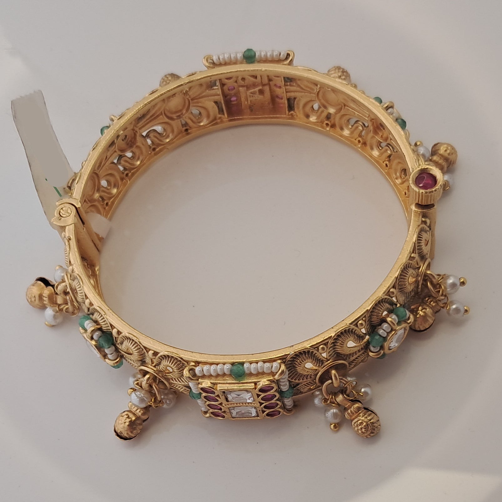 Decorative gold bracelet with gemstones on a white background