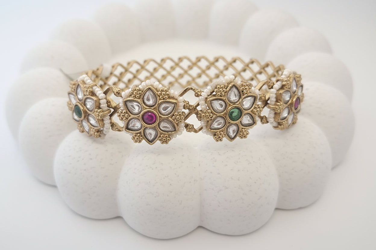 Decorative bracelet with floral designs and gemstones on a white background