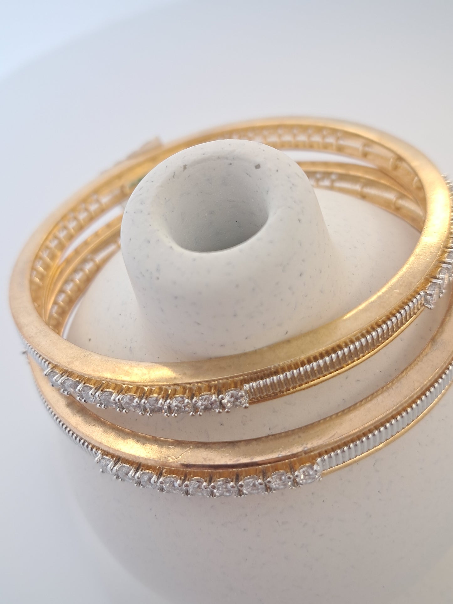 Gold bangles with diamond-like stones on a white background