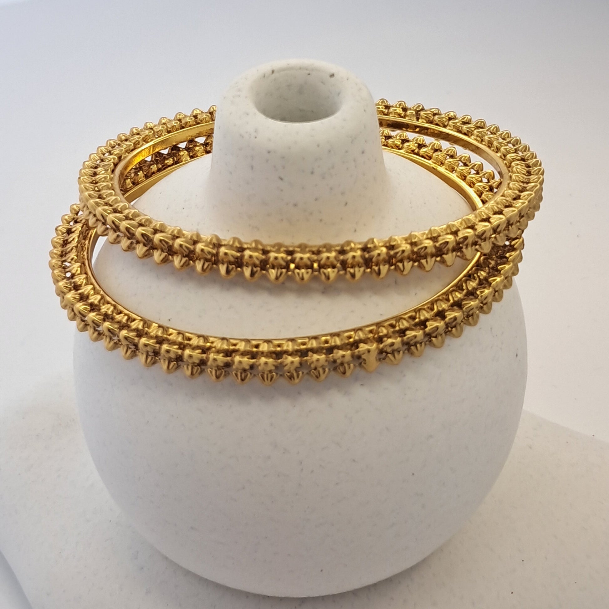 Gold bangles on a white stone surface