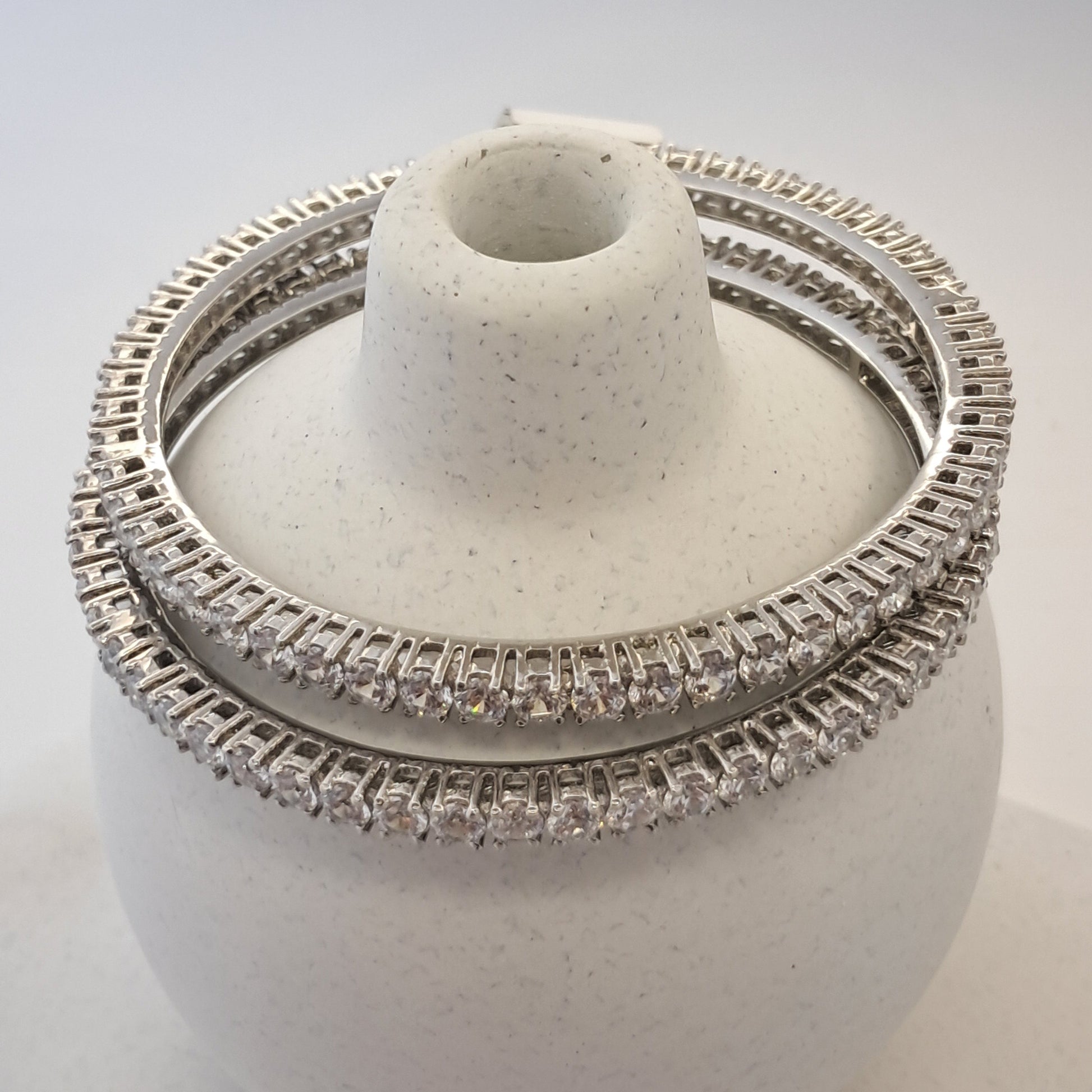 Silver ring with diamond accents on a white stand against a light gray background