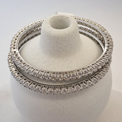 Silver ring with diamond accents on a white stand against a light gray background