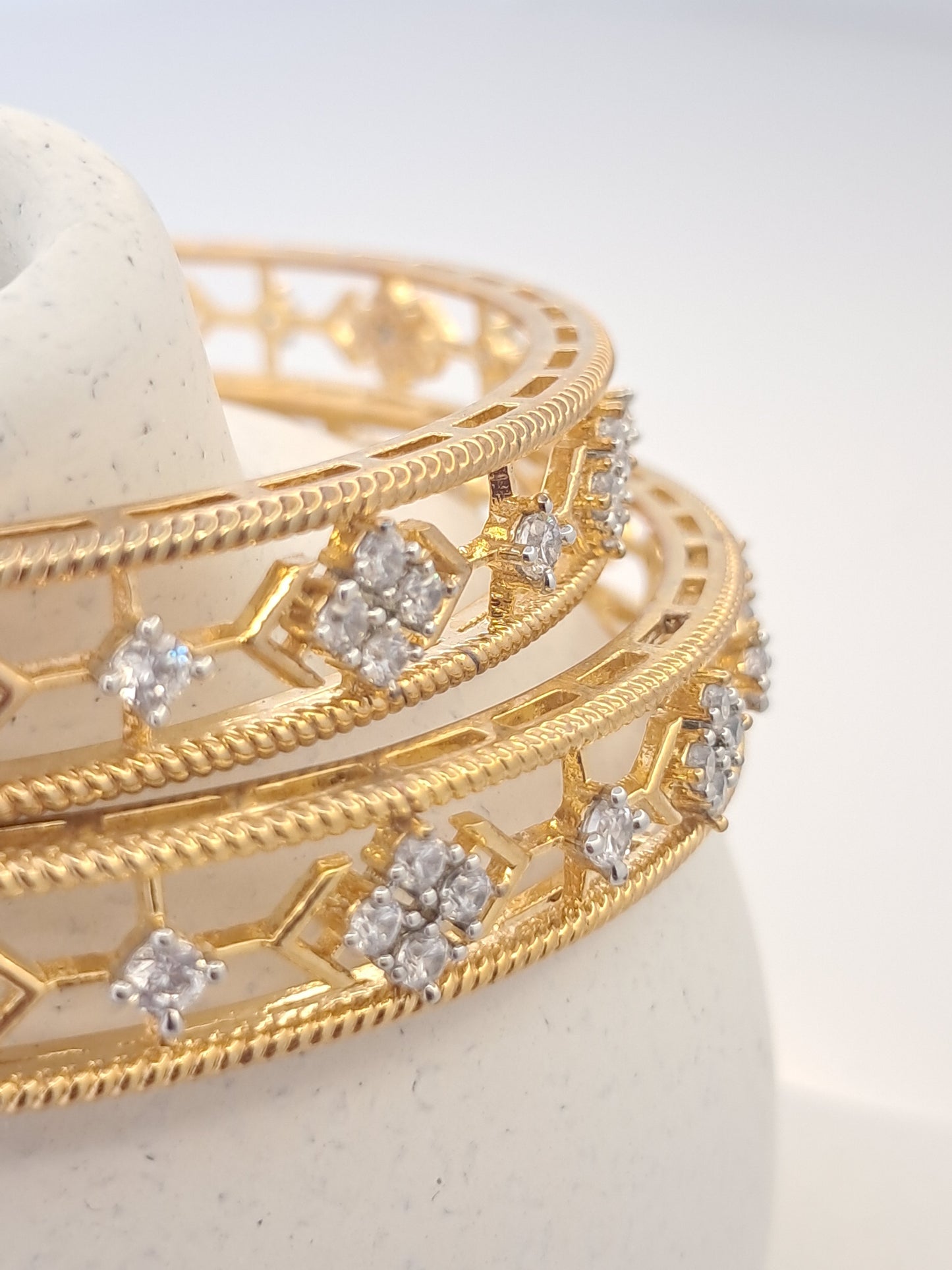 Gold bangles with diamond-like stones on a white background