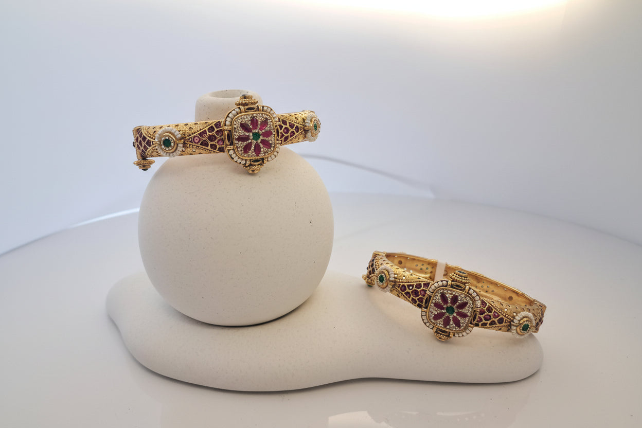 Gold bangles with gemstones on a white mannequin arm