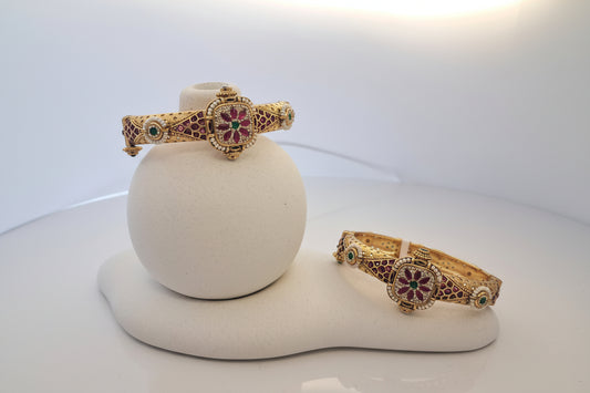 Gold bangles with gemstones on a white mannequin arm