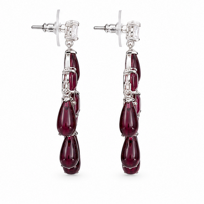 Four pairs of earrings displayed on a white background: two chandelier-style drop earrings with green stones at the top left, two chandelier-style drop earrings with red stones at the top right, and two matching dangle earrings with green stones at the bottom left, and two matching dangle earrings with red stones at the bottom right.