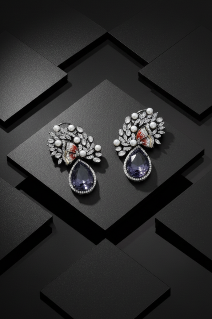 Pair of ornate earrings with gemstones on a black geometric background