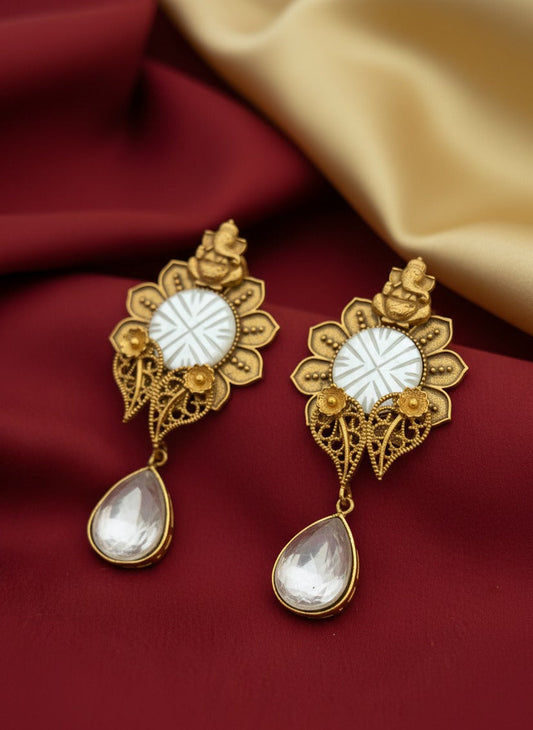Gold earrings with white stones on a red fabric background