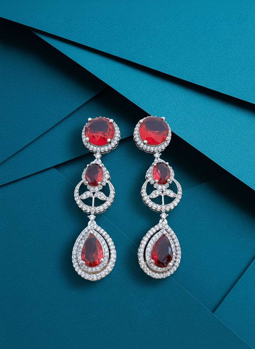 Pair of earrings with red gemstones on a blue background