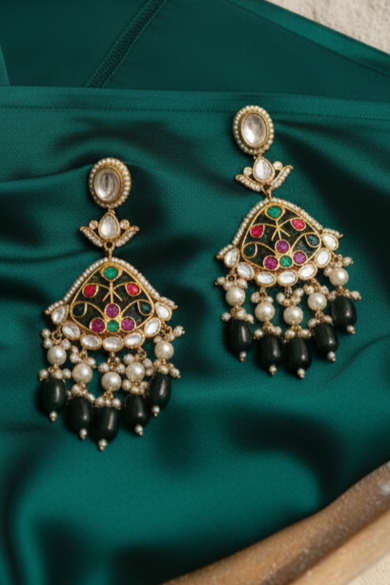 Ornate earrings on a green fabric with a neutral background