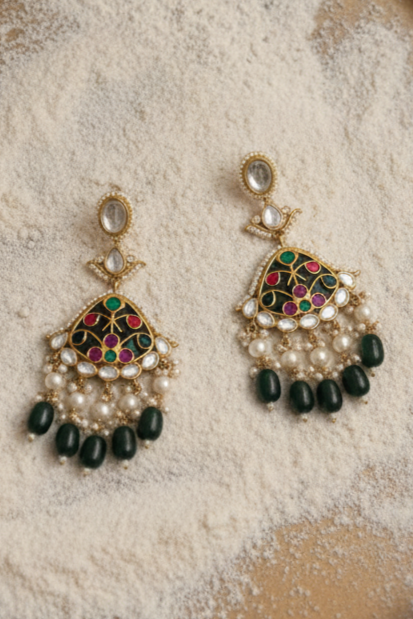 Ornate earrings with pearls and gemstones on a textured surface