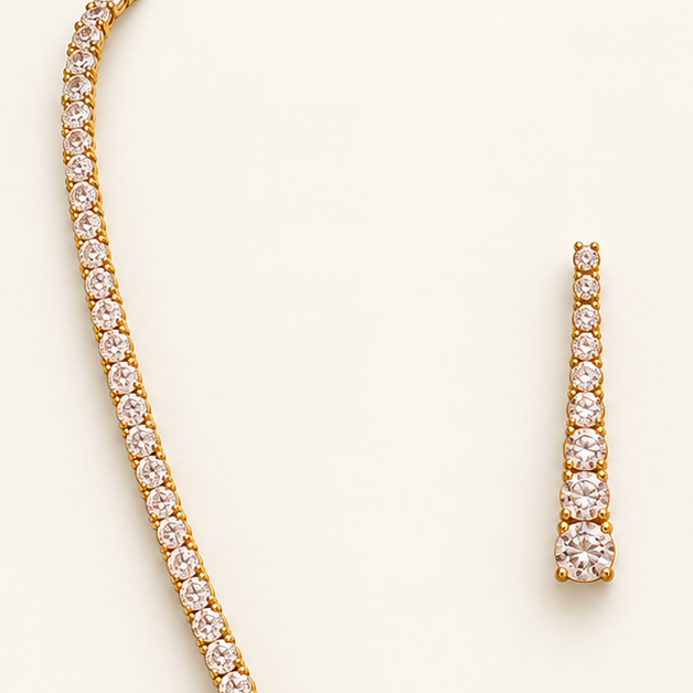 Gold necklace and matching drop earrings set with Cubic Zircon Triple "A" Quality, displayed on a light cream background.