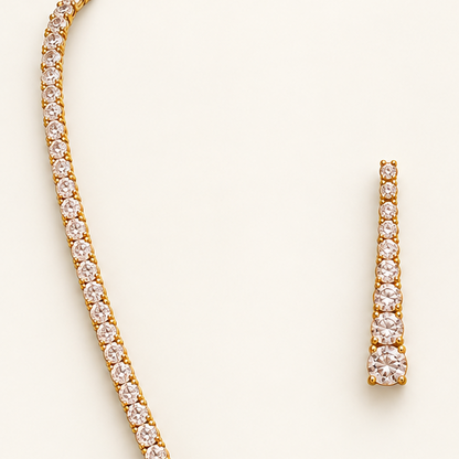 Gold necklace and matching drop earrings set with Cubic Zircon Triple "A" Quality, displayed on a light cream background.