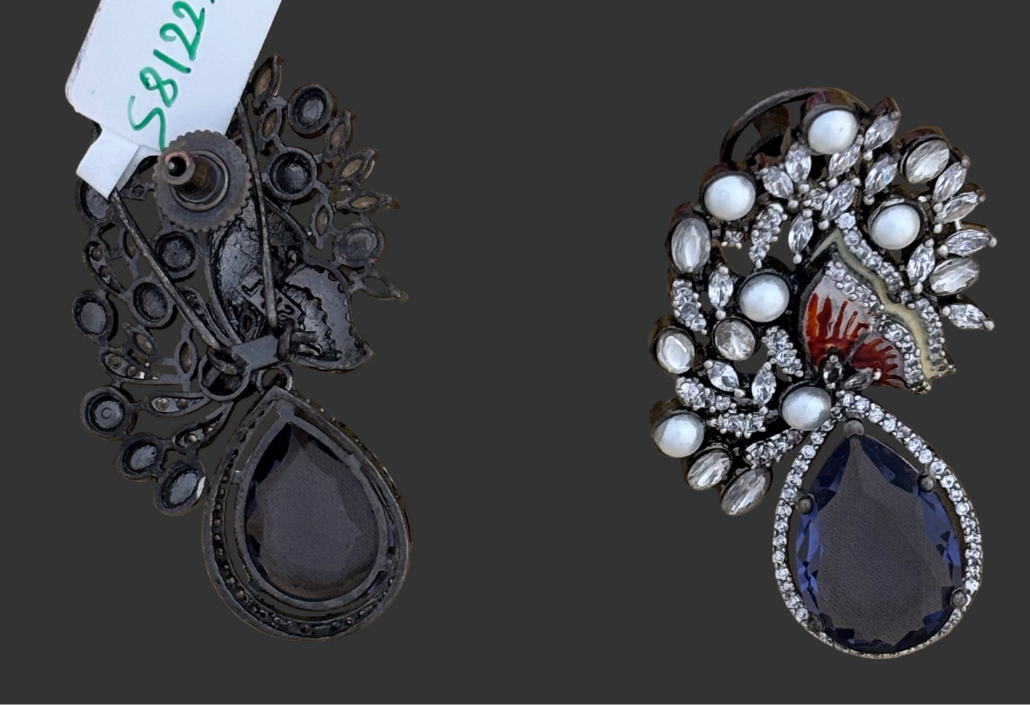 Pair of ornate earrings with teardrop-shaped stones on a dark background