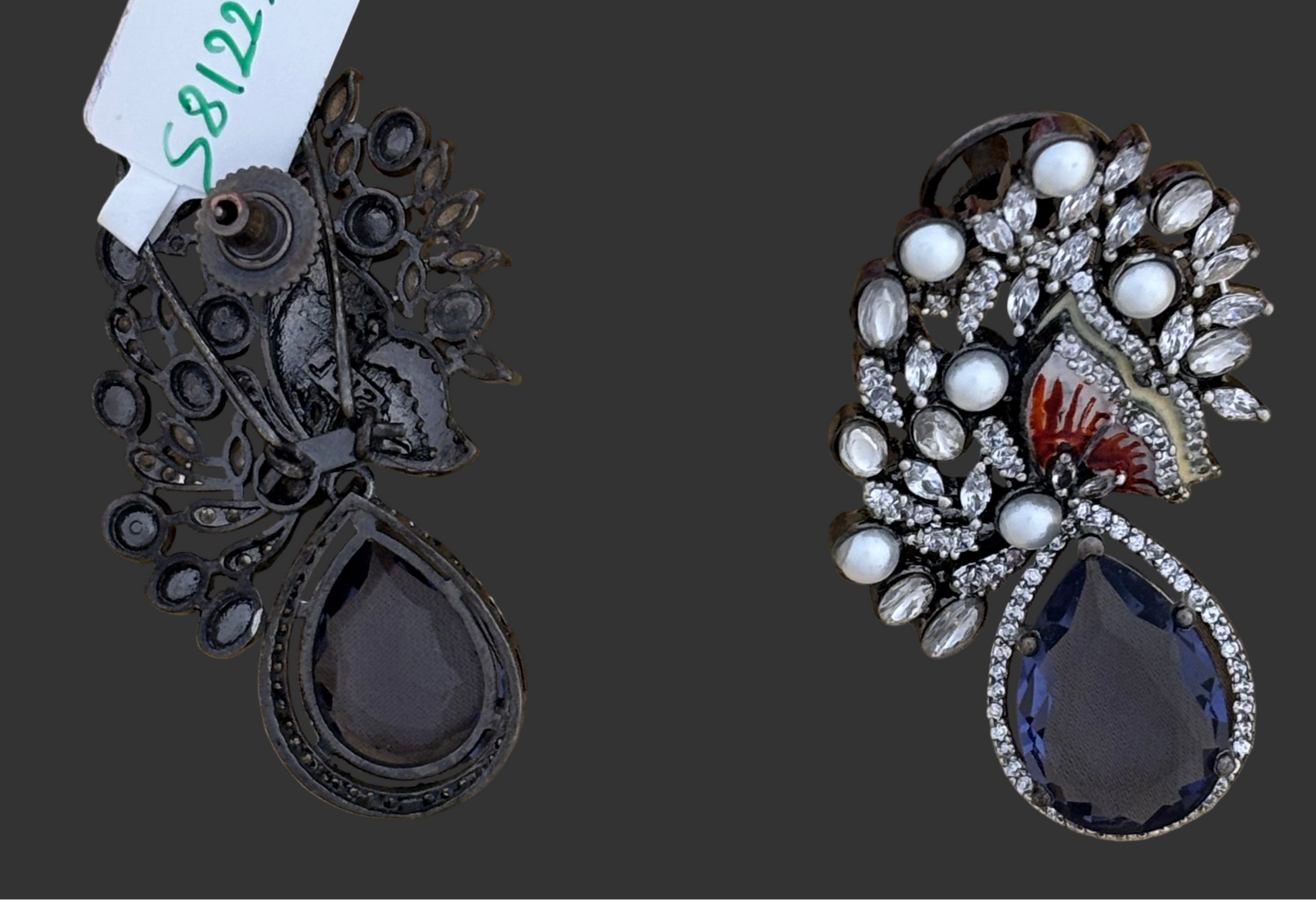Pair of ornate earrings with teardrop-shaped stones on a dark background