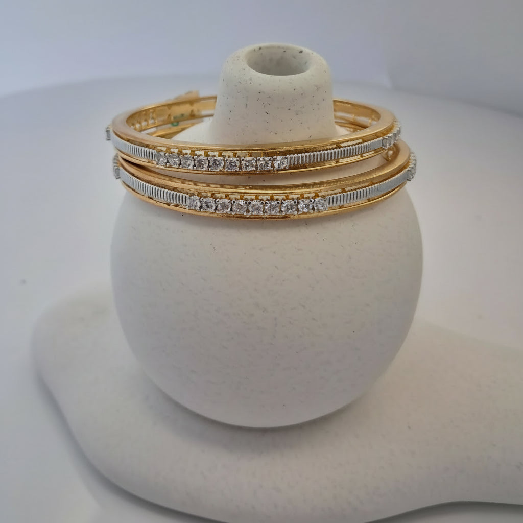 Gold bangles with diamond accents on a white stand