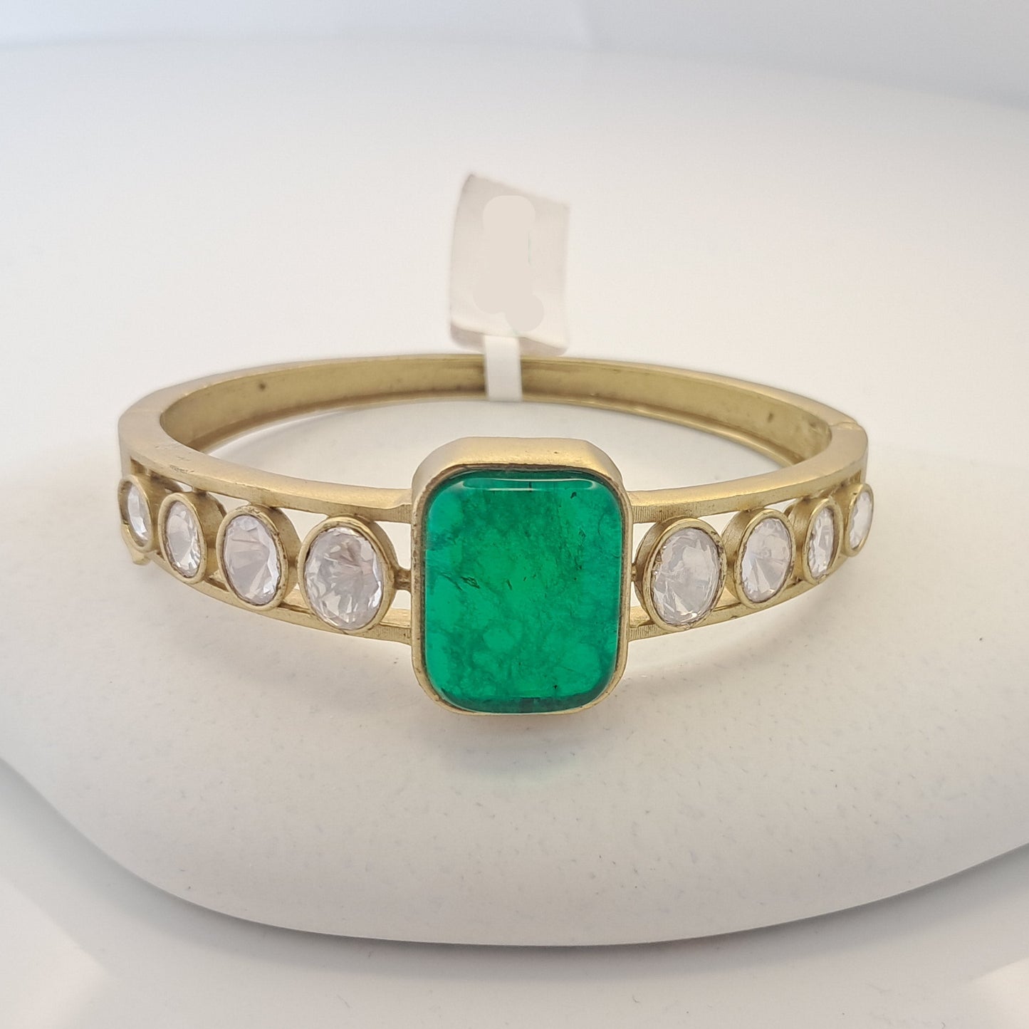 Gold ring with a green doublet gemstone and small diamonds on a white surface