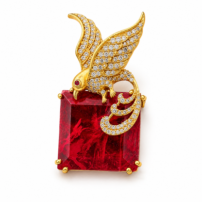 A gold-toned bird brooch with a winged head and tail details, set with small Cubic Zircon Triple "A" Quality, perched on a large square red gemstone. The brooch is photographed on a clean white background.