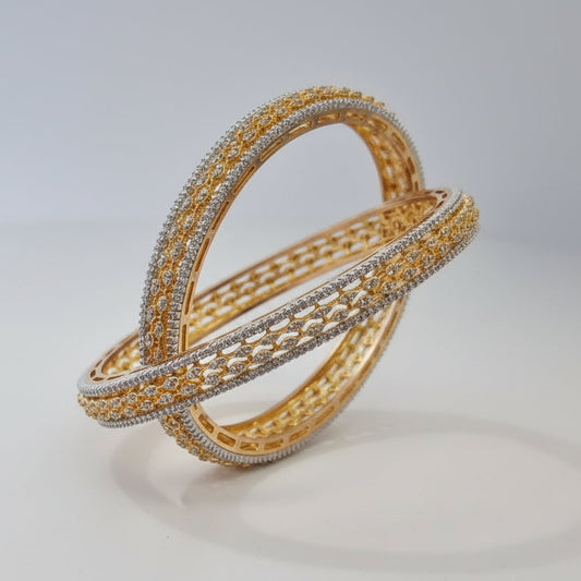 Pair of gold and silver bangles on a light gray background