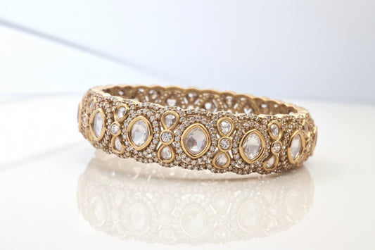 Decorative gold bangle with gemstones on a white background
