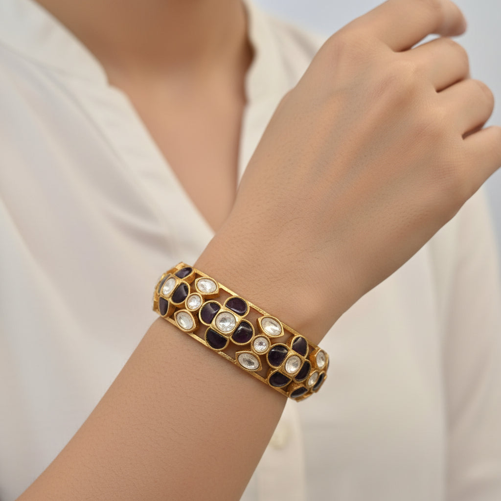 Gold bracelet with embedded stones on a white stand